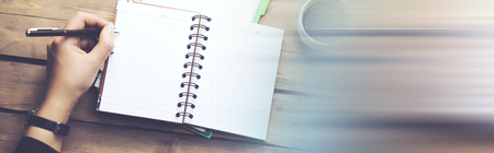 Woman hands with pen writing on notebook and coffee cup on  table