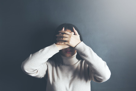 Portrait of a beautiful woman covering her eyes with her hands