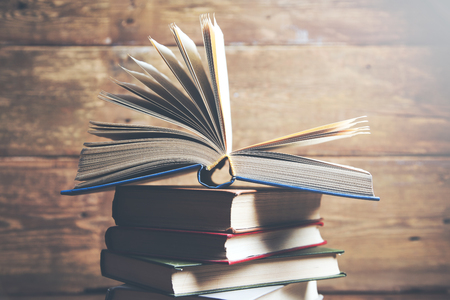 Open book, hardback books on wooden tableの写真素材