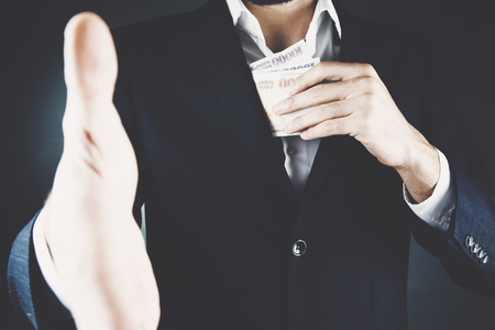 Business man hiding money in jacket pocketの写真素材