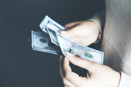 woman hand holding money on dark backgroundの写真素材