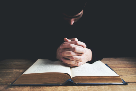 man hands praying with a bible in a dark over wooden table.の写真素材