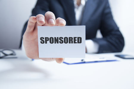 sponsored text on card on businessman handの写真素材