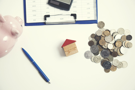 house model with coins and piggy bank on tableの写真素材
