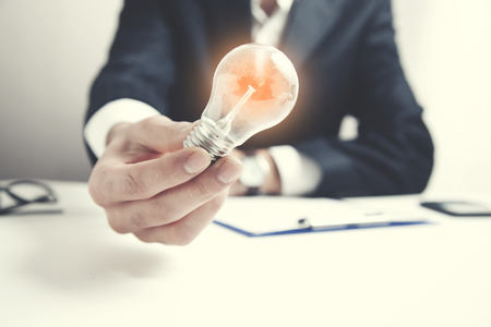 man hand idea or light bulb on tableの写真素材