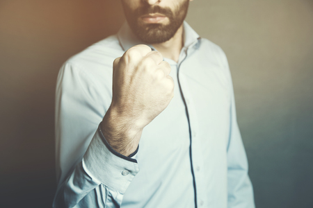 Business manager with clenched fist on dark backgroundの写真素材