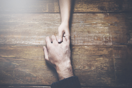 man and a woman holding hands at a wooden tableの写真素材