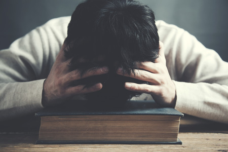 Depressed man hand in head on book