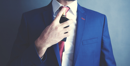 elegant young man is perfuming himselfの写真素材