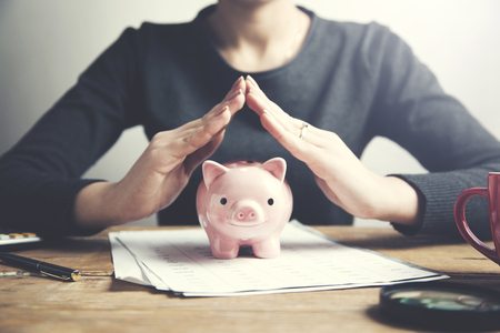 woman hand piggy bank on document on tableの写真素材