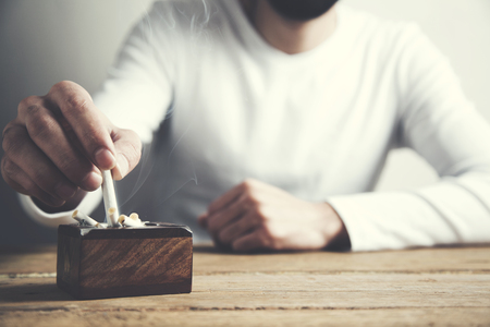 Hand putting out a cigarette in ashtrayの写真素材