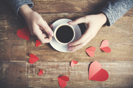 woman hand cup of coffee with heart for paper on tableの写真素材