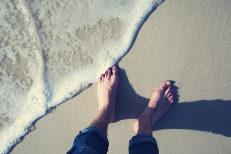 male feet walking at the  beach .