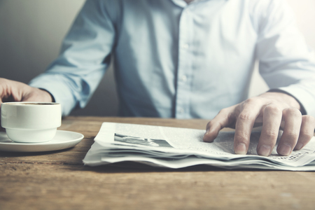 man reading newspaper and hand cup of coffeeの写真素材