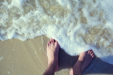 Detail of male feet walking at the beach