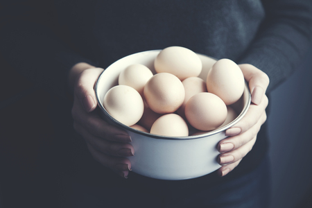 young woman holding a bowl of eggs の写真素材