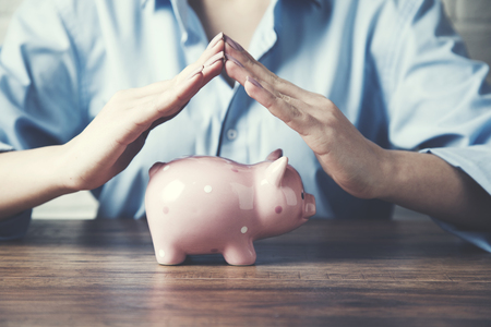 woman hand piggy bank on wooden tableの写真素材