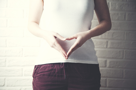 Close-Up Of Woman Making Heart Shape With Hands On Stomachの写真素材