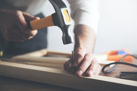 builder holding hummer and scored nail on deskの写真素材