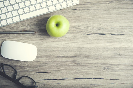 Working wooden gray desk with green apple