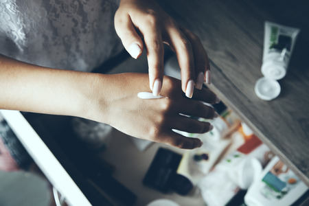 Female hands applying cream on the  deskの写真素材