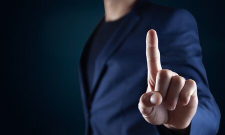 Businessman pressing button on virtual screen on the dark background