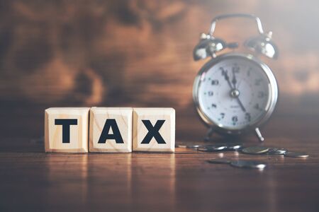 tax text on cubes with coins and clockの写真素材
