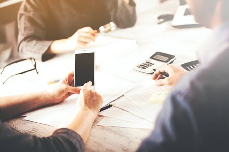 woman hand phone with team work in office table