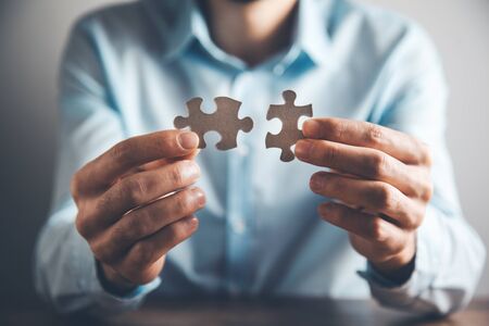 Businessman holding two matching puzzle pieces together