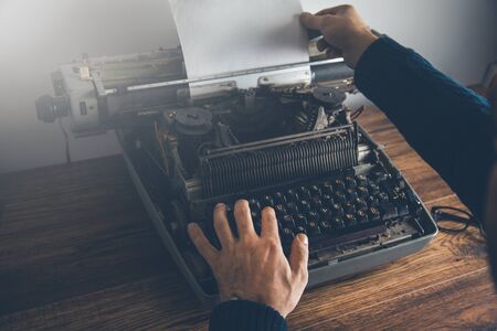 male hands writing an typewriter on tableの写真素材