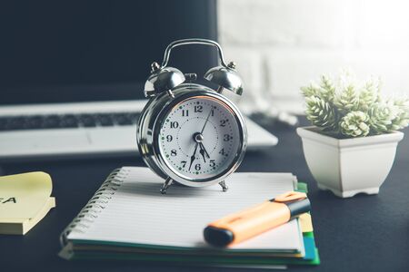 clock on notepad with keyboard on tableの写真素材