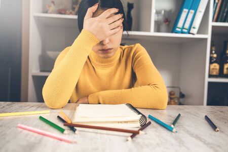 sad woman with notepad and pencils on table