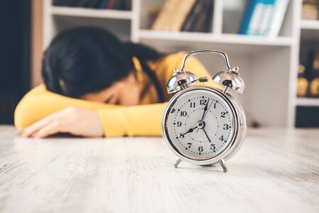 woman sleeping on table with clock