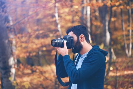 photographer hand camera in autumn forestの写真素材