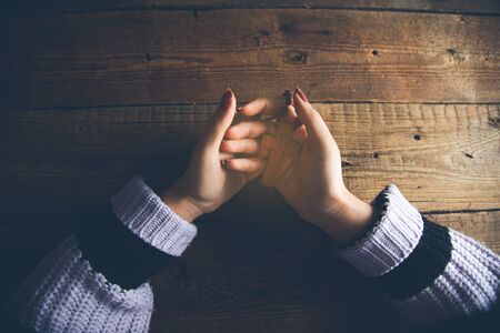 woman hand holding cross with book on table