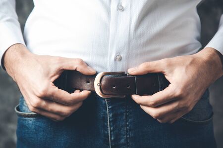man hand on belt on dark backgroundの写真素材