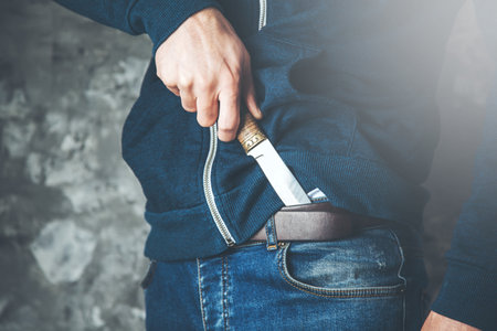 man hand knife on trousers on the dark backgroundの写真素材