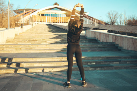 Rear view of woman stretching with arms raised