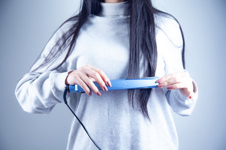 young woman hand hair dryer on the dark backgroundの写真素材