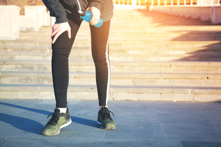 young runner woman hand bottle in road