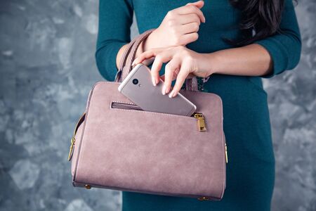 woman hand phone on bag pocket on gray backgroundの写真素材