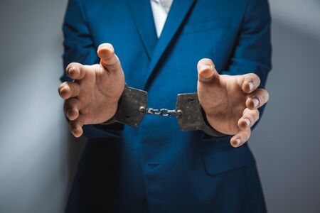 young man hand handcuffs on dark backgroundの写真素材
