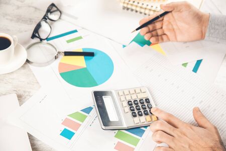 man hand calculator with graph document on desk