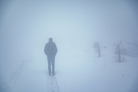 man in winter fog mountain road background
