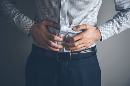young business man has stomachache on grey background