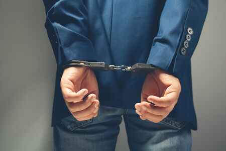 man hand handcuffs in backon grey backgroundの写真素材