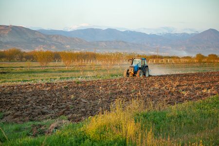 tractor in field at the sunset and mountain background