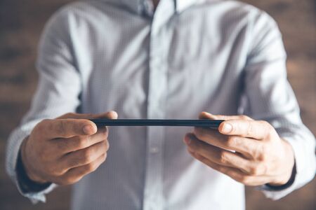 man tand holding tablet on brown background