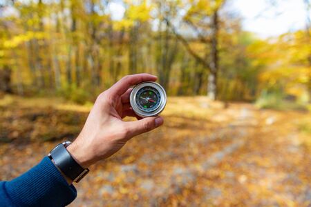 man hand compass with autumn  forest backgroundの写真素材