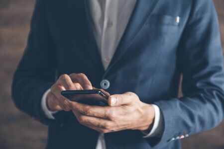 young man hand smart phone on brown background
